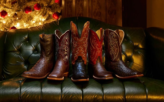 Image of a row of Tony Lama boots on a green couch with a Christmas tree in the background.